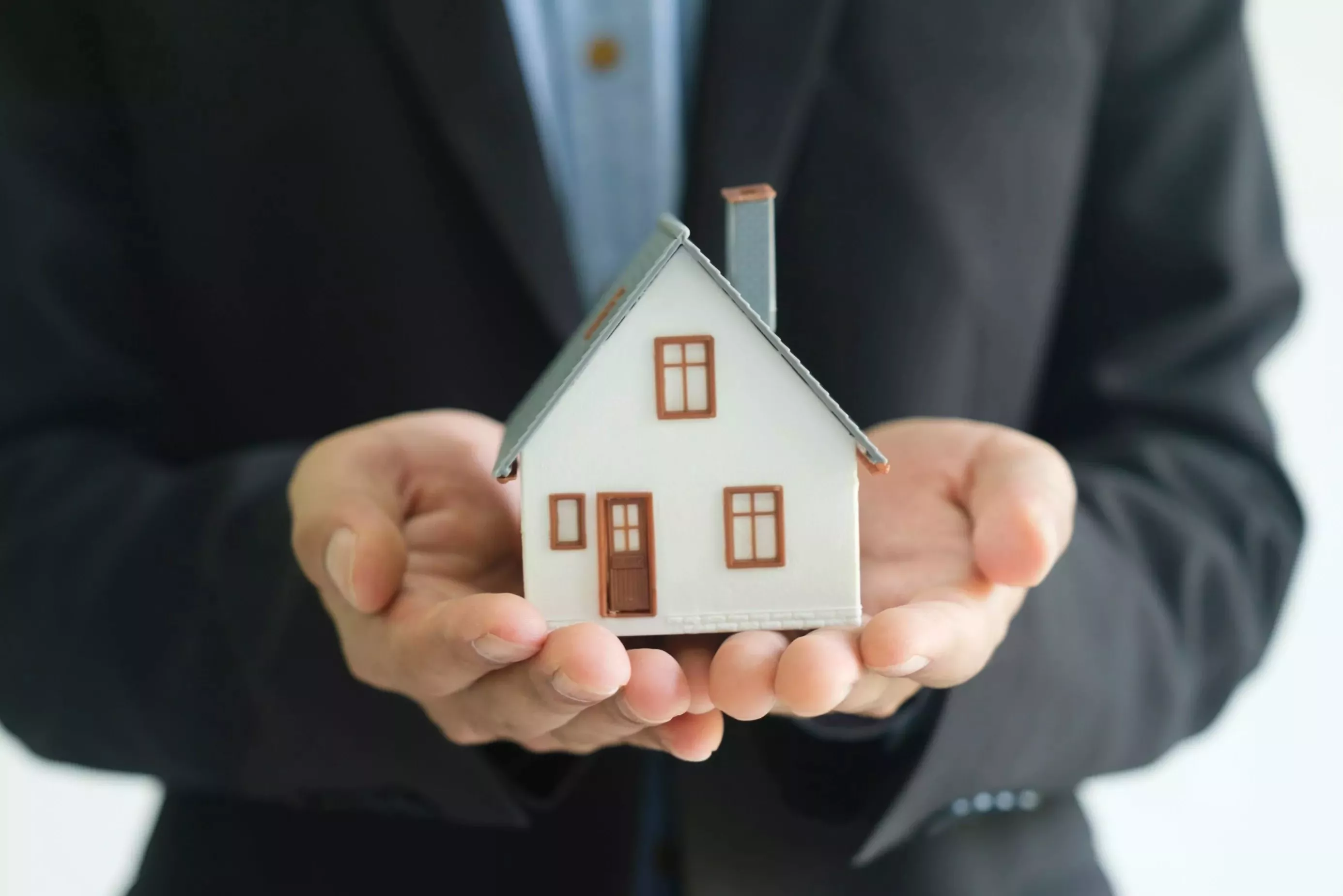 Person, die ein Modell-Haus in den Händen hält